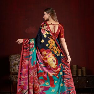 A woman in a vibrant floral saree poses indoors against a red wall, embodying traditional Indian attire.
